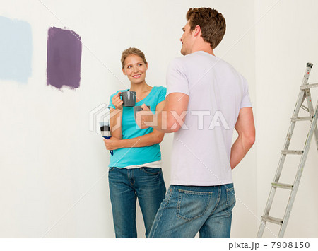 Young couple looking at paint on wall Young couple looking at paint on wall 7908150