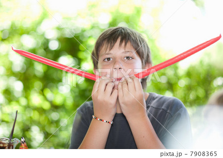 Boy blowing noisemakers at party 7908365