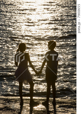 Teenage couple watching sunset over sea 7908655