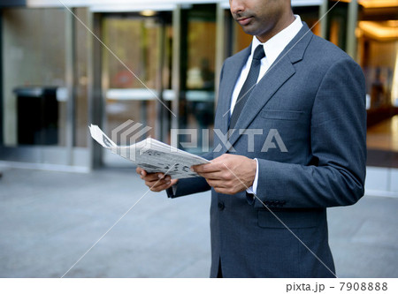 Businessman reading a newspaper outside building 7908888