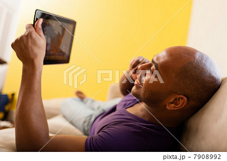 Mid adult male on sofa holding digital tablet and mobile phone Mid adult male on sofa holding digital tablet and mobile phone 7908992