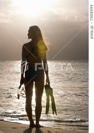 Silhouette of woman at water's edge, Mustique, Grenadine Islands 7908994