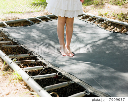 Girl bouncing on trampoline, low section Girl bouncing on trampoline, low section 7909037