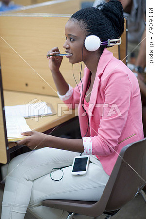 Female student working in library with headphones 7909038