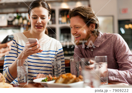 Friends at restaurant texting and showing photos using cell phones 7909222