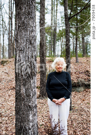 Portrait of senior woman in forest, hands clasped 7909438