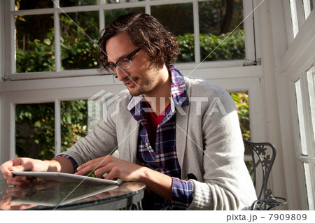 Man using tablet computer at table 7909809