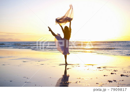 Young woman dancing on sunlit beach 7909817