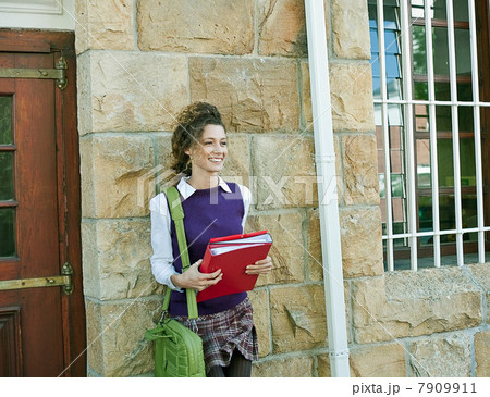 Student holding folders outside building Student holding folders outside building 7909911