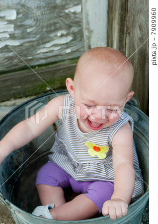 Baby sitting in a bucket and laughing Baby sitting in a bucket and laughing 7909960