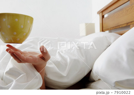 Person under duvet being handed a coffee 7910022