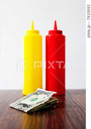Money on table next to mustard and tomato sauce Money on table next to mustard and tomato sauce 7910092
