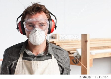 Carpenter wearing dust mask and ear defenders, portrait 7910262