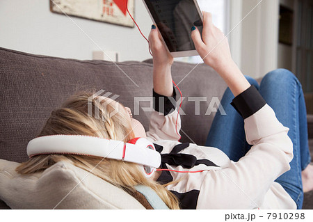 Girls lying on sofa using digital tablet Girls lying on sofa using digital tablet 7910298