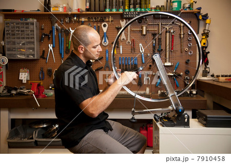 Man fixing bicycle rim in workshop 7910458