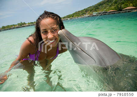 Young woman smiling with dolphin in sea Young woman smiling with dolphin in sea 7910550