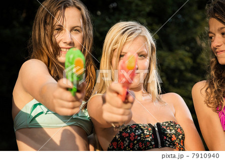 Girls aiming water pistols at camera 7910940