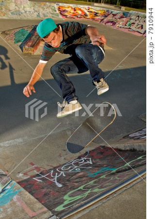 Skateboarder jumping on half pipe 7910944