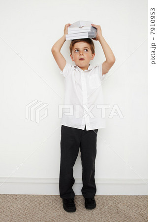 Schoolboy holding books on his head 7910953