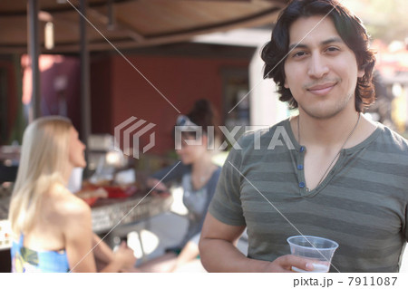 Young man holding drink and smiling in outdoor cafe, portrait Young man holding drink and smiling in outdoor cafe, portrait 7911087