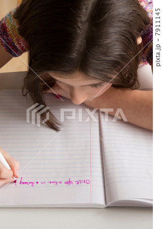 Girl writing in pink felt tip pen in notebook 7911145
