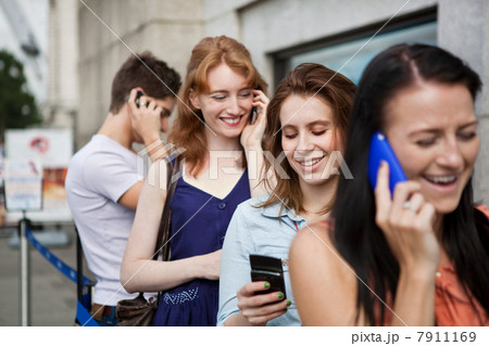 Four people in a queue, all using mobile phones 7911169
