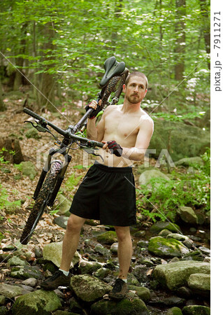 Male cyclist carrying bike in forest 7911271