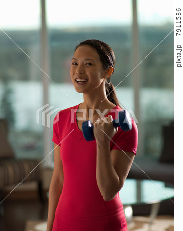 Woman lifting weights in living room 7911536