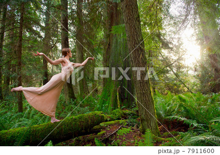 Mature woman standing on log in forest 7911600