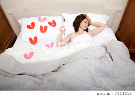 Woman crying in bed with broken heart shapes on bedclothes Woman crying in bed with broken heart shapes on bedclothes 7911619
