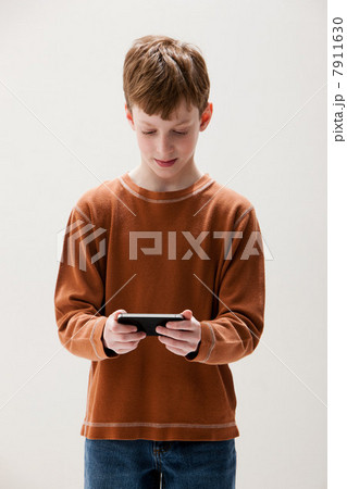 Boy in brown sweater playing hand held video game, studio shot Boy in brown sweater playing hand held video game, studio shot 7911630