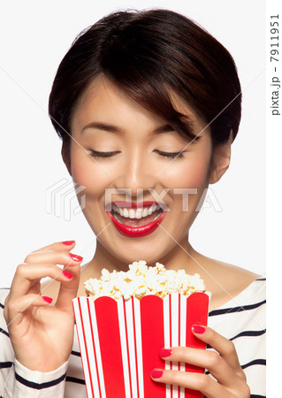 Young woman eating popcorn, studio shot Young woman eating popcorn, studio shot 7911951