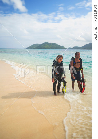 Scuba divers walking on tropical beach 7911998