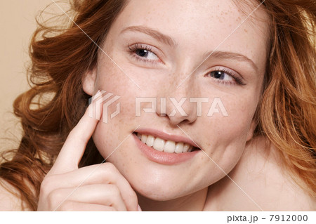 Studio shot of young woman with curly red hair, hand on chin pointing Studio shot of young woman with curly red hair, hand on chin pointing 7912000