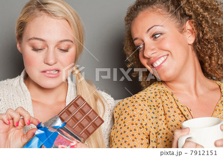 Woman staring at friend holding chocolate Woman staring at friend holding chocolate 7912151