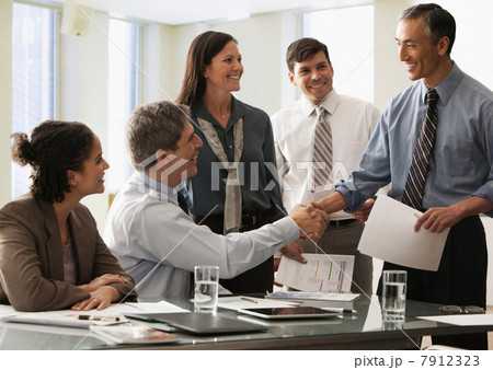 Businessman shaking hands in office with colleagues Businessman shaking hands in office with colleagues 7912323