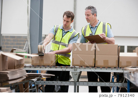 Men packing cardboard box in warehouse 7912340