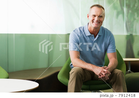 Portrait of mature man sitting in green chair in office 7912418