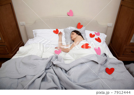 Woman asleep in bed with heart shapes on bedclothes Woman asleep in bed with heart shapes on bedclothes 7912444