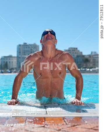 Young man exiting swimming pool 7912811