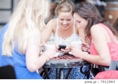 Three young women showing photos to each other 7912964