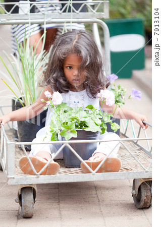 Girl sitting in cart at flower nursery Girl sitting in cart at flower nursery 7913104