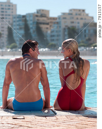 Young couple sitting at poolside Young couple sitting at poolside 7913157