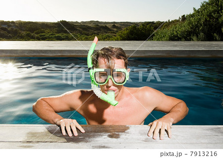 Young man wearing snorkel at poolside Young man wearing snorkel at poolside 7913216