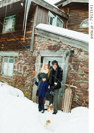 Family outside rustic house in snow 7913541