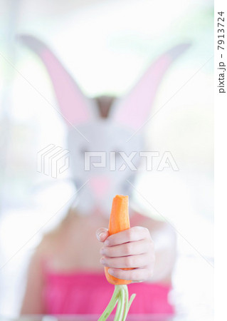 Girl in rabbit costume eating carrot 7913724