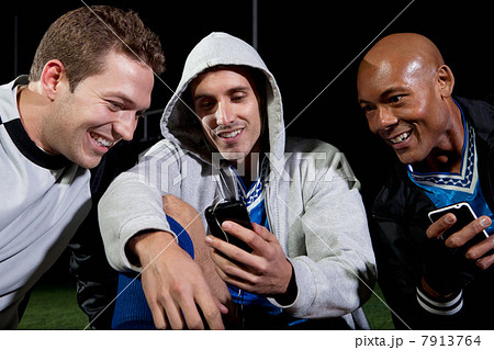 Soccer players looking at cellphone on pitch 7913764