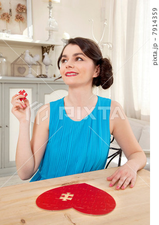 Woman doing heart shaped jigsaw puzzle holding piece 7914359