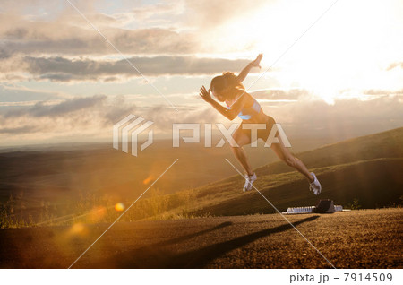 Young woman moving off starting blocks in rural setting Young woman moving off starting blocks in rural setting 7914509