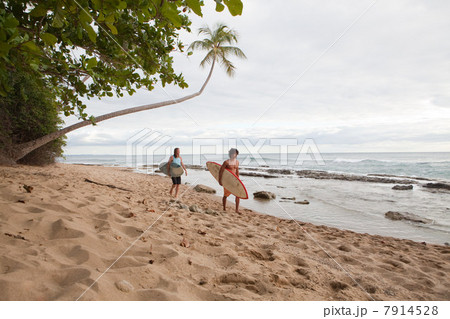 Two men carrying surfboards on beach Two men carrying surfboards on beach 7914528